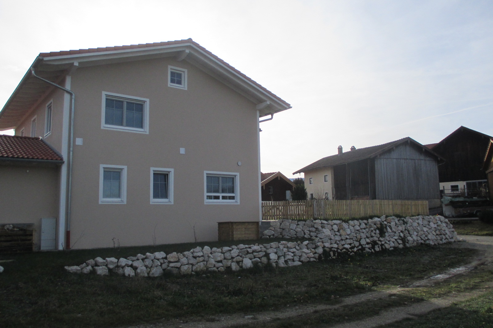 Einfamilienhaus mit Natursteinmauer und Holzzaun